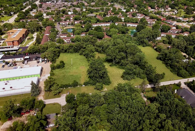 an aerial view of residential houses with outdoor space and trees