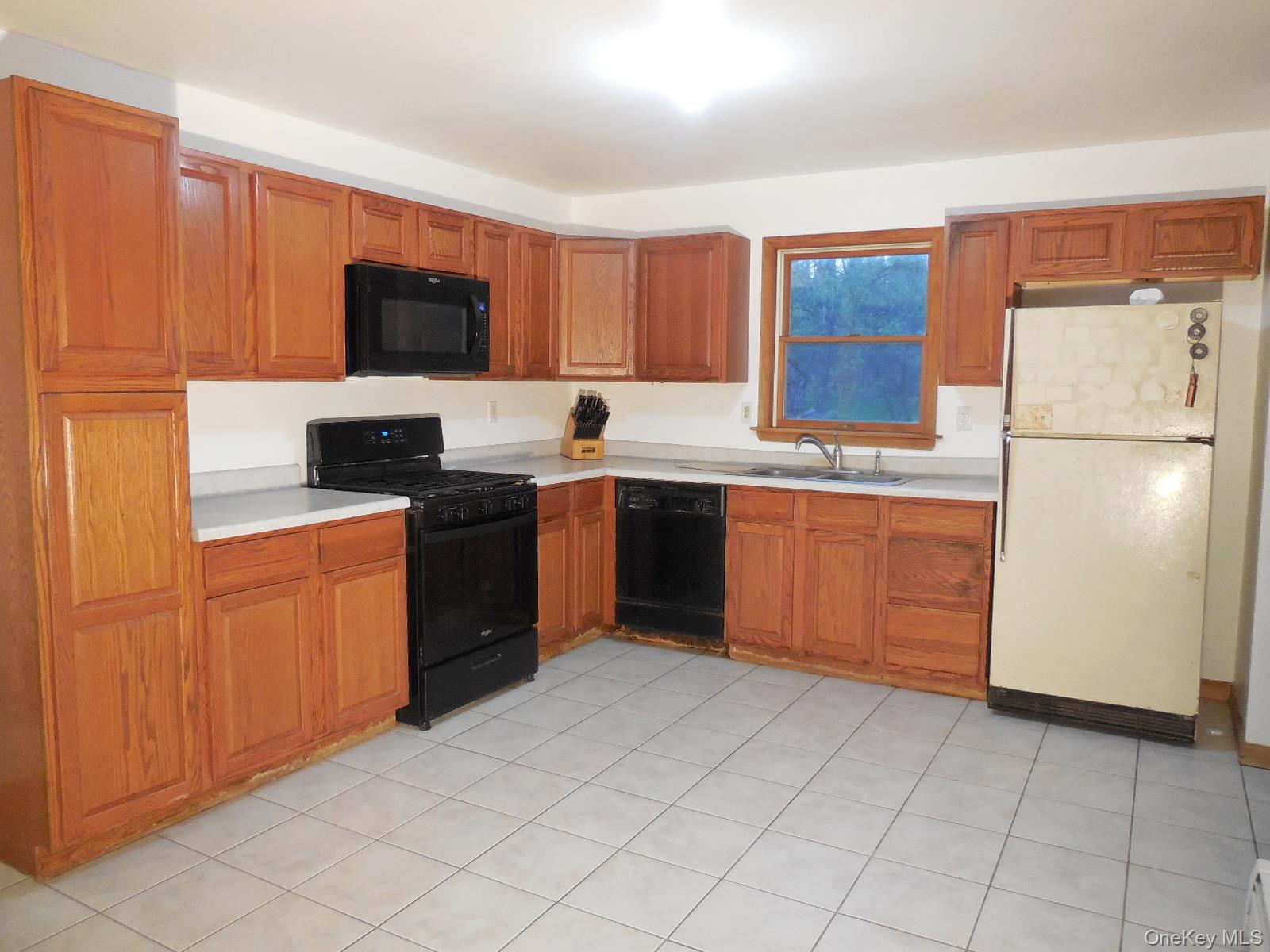 617 Burlingham Road Bloomingburg, NY 12721 - Photo 4 of 39 Kitchen featuring wood cabinetry, tile flooring, window above sink and side entry door to the left.