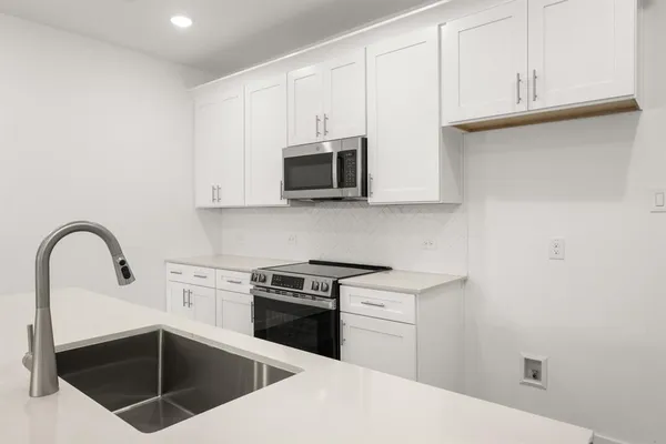a kitchen with stainless steel appliances granite countertop a stove a microwave and a sink