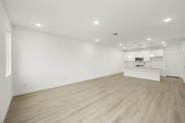 a view of kitchen with kitchen island a sink wooden floor and view living room