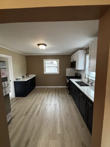 a kitchen with stainless steel appliances a sink dishwasher stove refrigerator and wooden floor