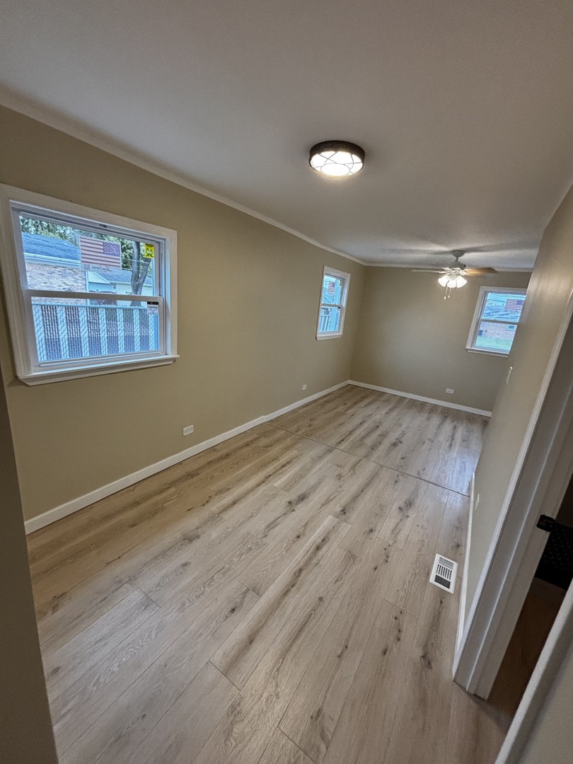 7722 West 81st Place Bridgeview, IL 60455 - Photo 7 of 13 an empty room with wooden floor and windows
