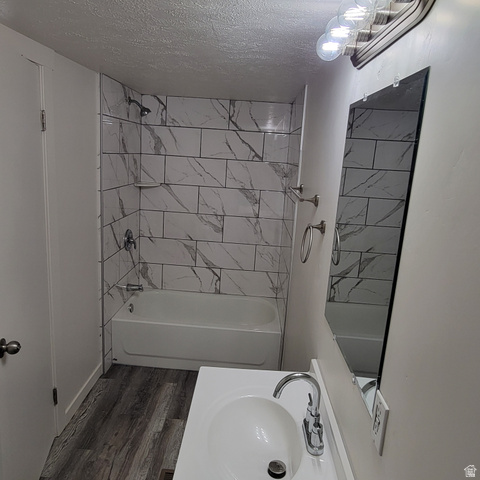 1735 South 1380 West Logan, UT 84321 - Photo 29 of 46 Bathroom featuring a white bathtub with marble-look subway tile surround, chrome fixtures, wood-finish flooring, a white vanity with integrated sink, and a wall-mounted mirror