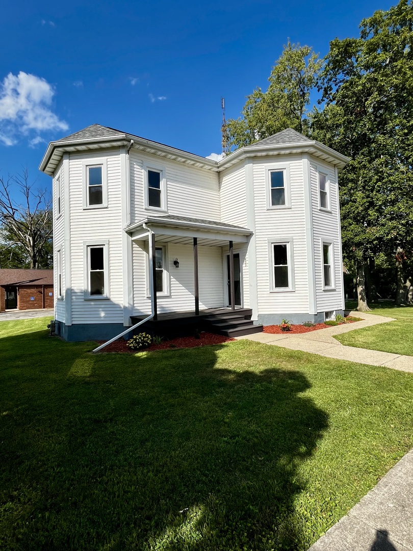 403 Uncas Street Tonica, IL 61370 - Photo 2 of 30 a view of a white house with a big yard and potted plants