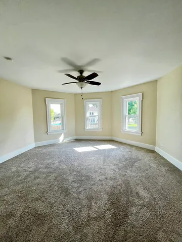 an empty room with windows and ceiling fan
