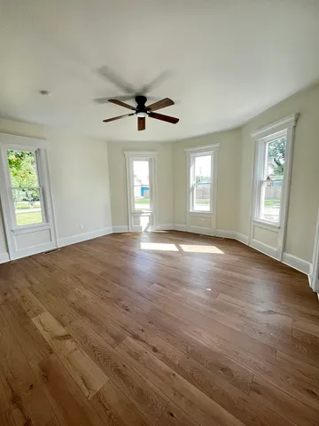 a view of an empty room with window and wooden floor