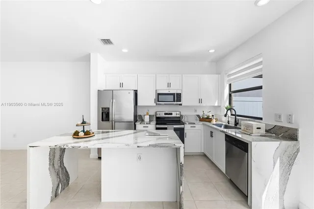 a kitchen with kitchen island a sink stove and refrigerator