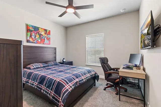 a bedroom with a bed a computer on a desk and chair