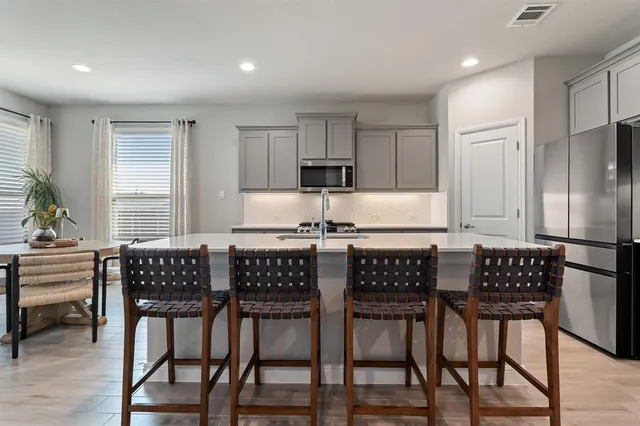 a kitchen with a dining table chairs and refrigerator