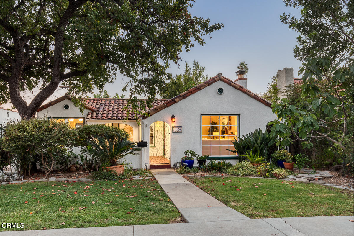 a view of a white house next to a yard with big trees