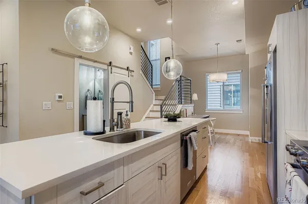a kitchen with stainless steel appliances granite countertop a sink a stove and a wooden floors
