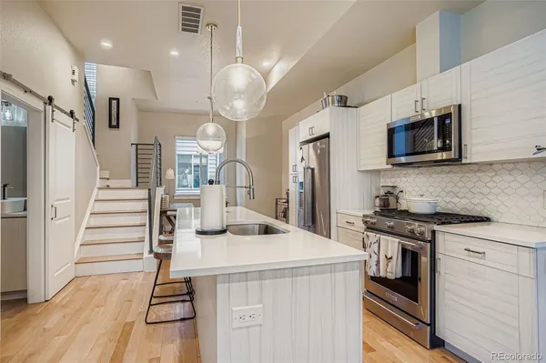 a kitchen with stainless steel appliances kitchen island granite countertop a stove a sink and a refrigerator