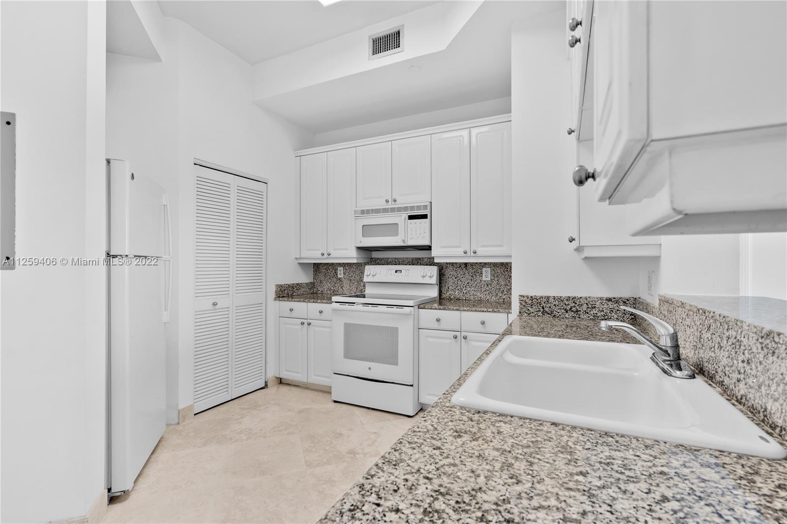 888 Brickell Key Drive, Unit 2610 Miami, FL 33131 - Photo 12 of 31 a kitchen with granite countertop white cabinets and white appliances