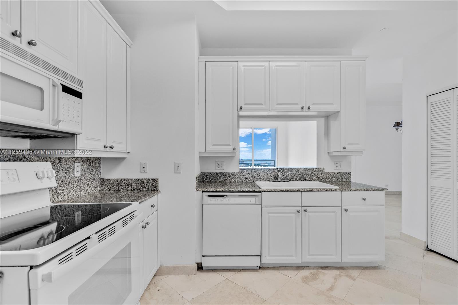 888 Brickell Key Drive, Unit 2610 Miami, FL 33131 - Photo 13 of 31 a kitchen with granite countertop white cabinets and white appliances