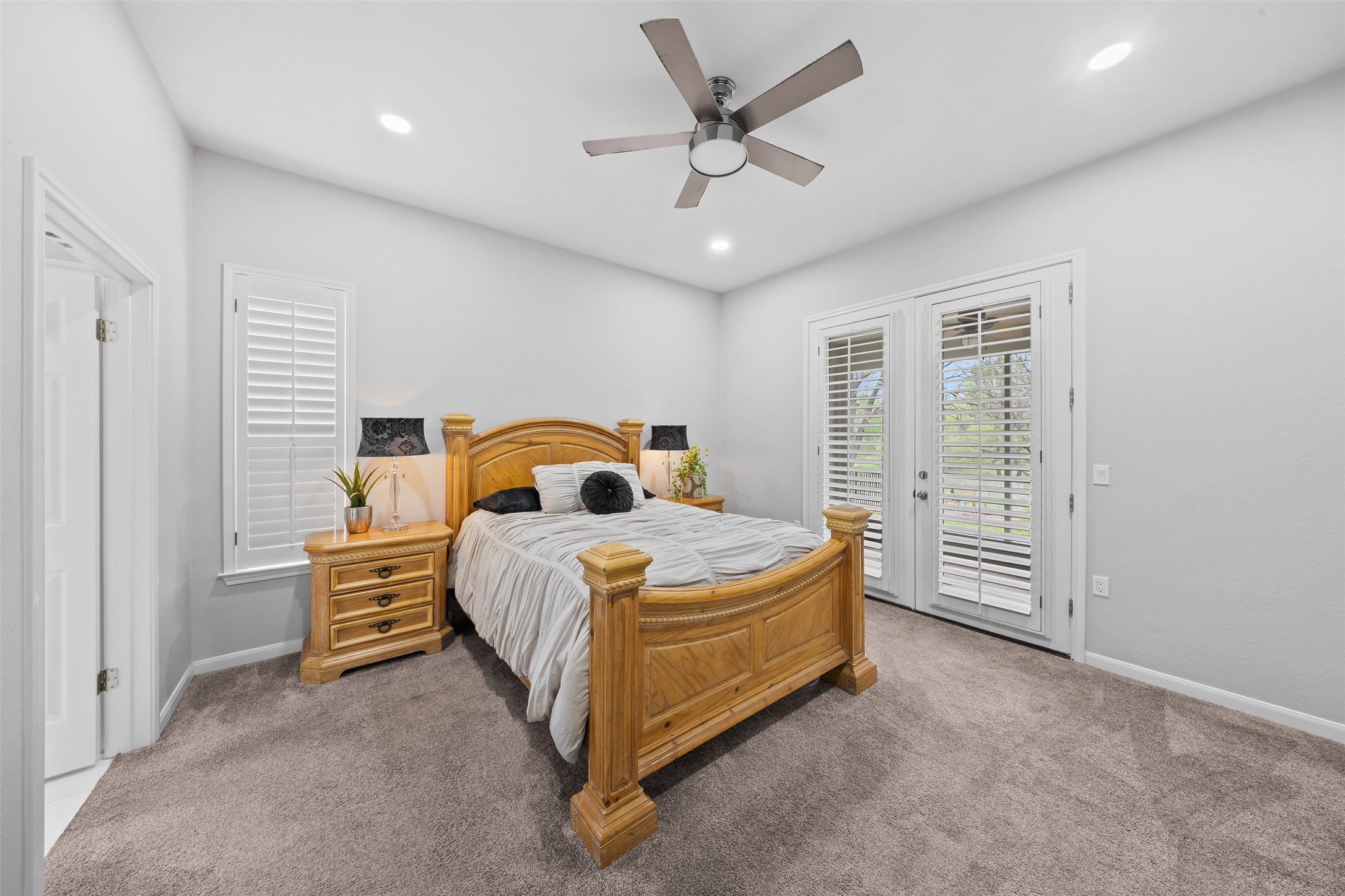 144 Stetson Trail Georgetown, TX 78633 - Photo 23 of 39 Carpeted primary bedroom with ensuite bathroom, access to outside through beautiful french doors, modern ceiling fan, and recessed lighting
