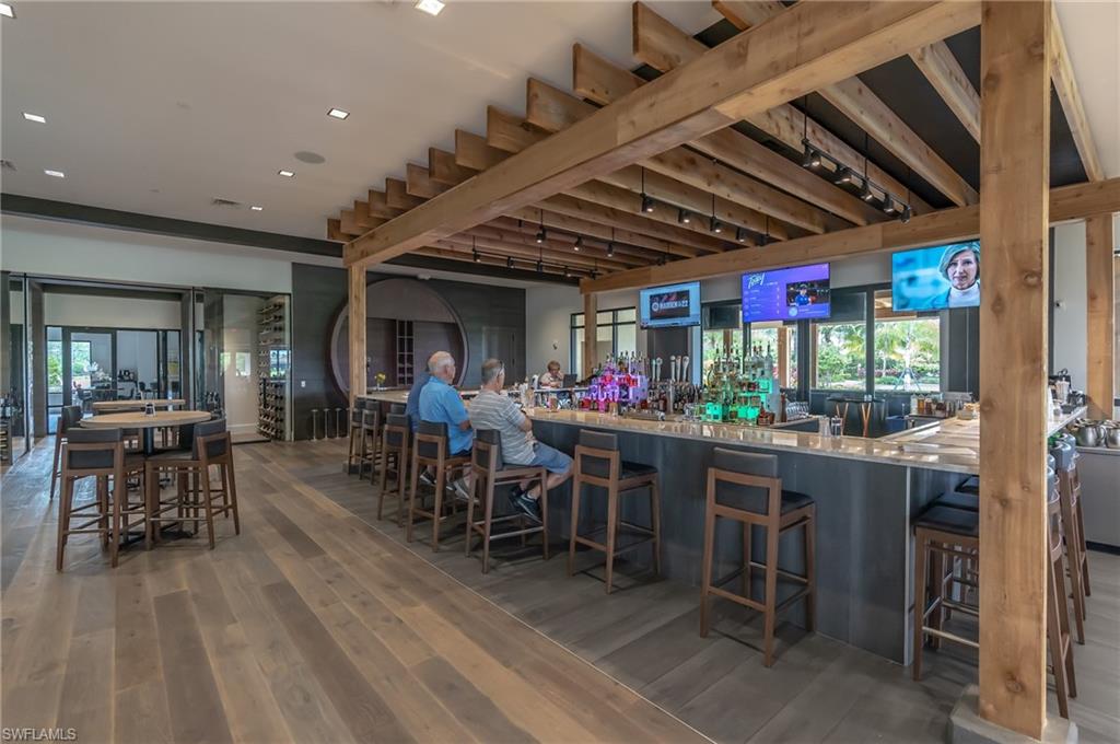 9419 Benvenuto Court, Unit 204 Naples, FL 34119 - Photo 15 of 50 Community bar area with dark wood-style floors, light stone countertops, and recessed lighting