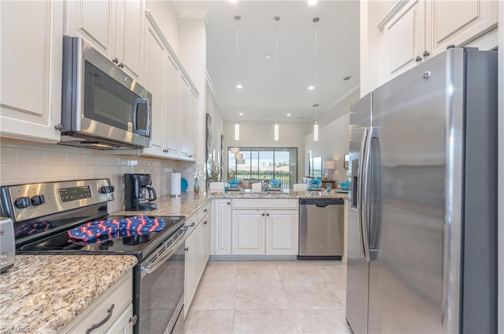 9419 Benvenuto Court, Unit 204 Naples, FL 34119 - Photo 22 of 50 Kitchen featuring stainless steel appliances, decorative light fixtures, light stone counters, backsplash, and white cabinetry