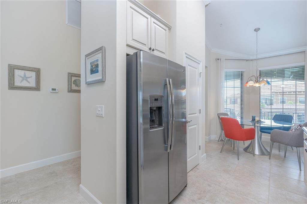9419 Benvenuto Court, Unit 204 Naples, FL 34119 - Photo 24 of 50 Kitchen with stainless steel refrigerator with ice dispenser, decorative light fixtures, white cabinetry, a chandelier, and crown molding