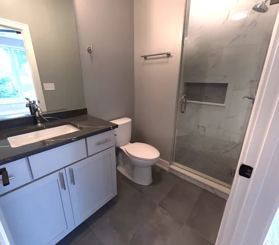 a bathroom with a granite countertop sink toilet and shower