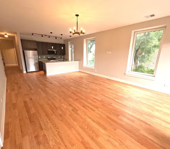 a view of a kitchen with kitchen island a window wooden floor and stainless steel appliances