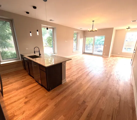 a kitchen with stainless steel appliances granite countertop a sink a stove a refrigerator wooden floor and a large window