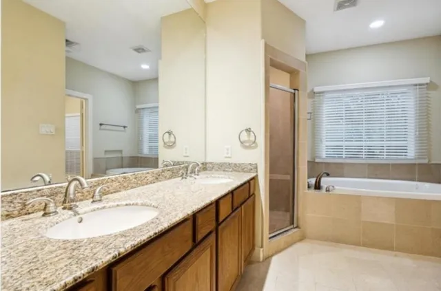 a bathroom with a granite countertop bathtub a sink and a large mirror