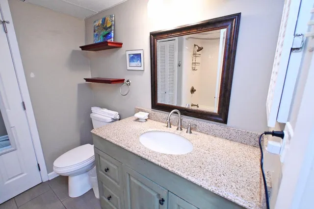 a bathroom with a granite countertop sink a toilet and a mirror
