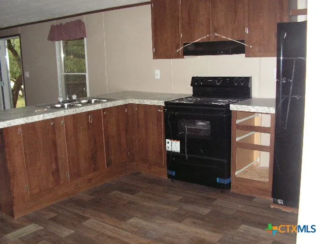 a kitchen with granite countertop a refrigerator and a stove top oven