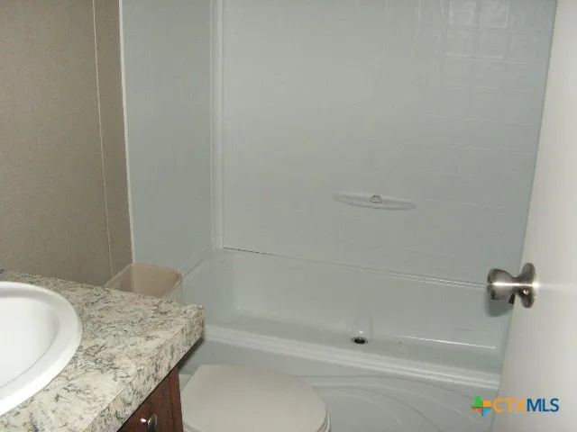 a bathroom with a granite countertop sink a toilet and bathtub