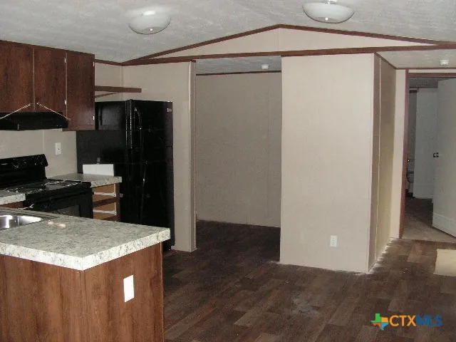 a kitchen with granite countertop a refrigerator a stove and a sink