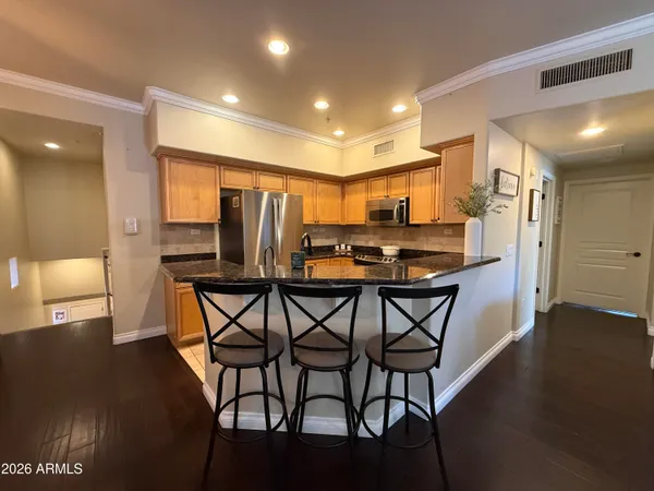 a kitchen with stainless steel appliances a dining table chairs and wooden floor