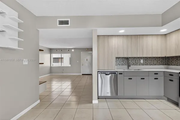 a view of an empty room with window and cabinet area