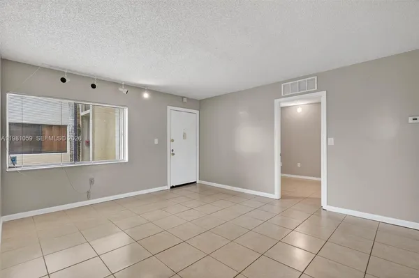 a view of an empty room with window and chandelier