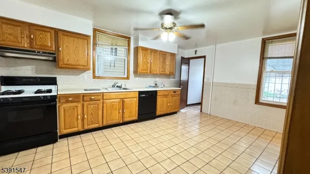 a kitchen with stainless steel appliances a sink a stove a refrigerator cabinets and a window