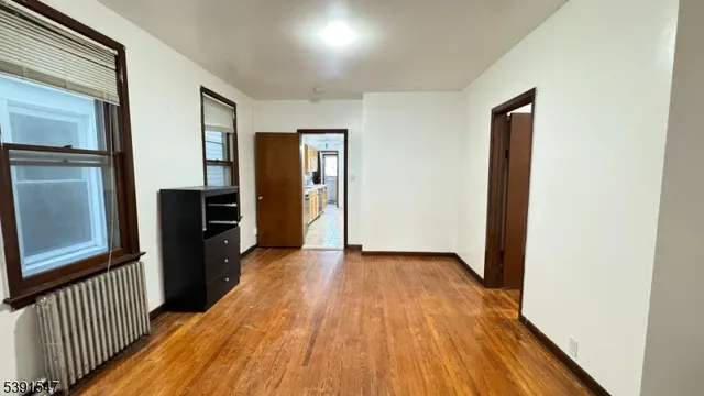 an empty room with wooden floor closet and windows