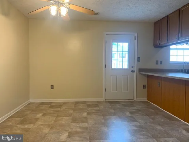 an empty room with a chandelier fan and windows