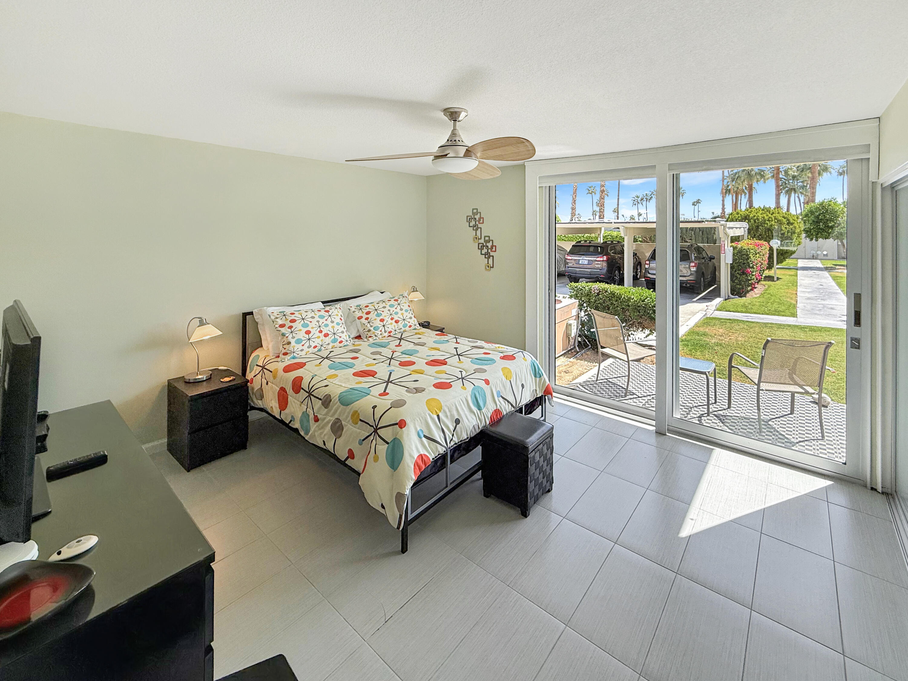 1881 South Araby Drive, Unit 16 Palm Springs, CA 92264 - Photo 22 of 52 a bedroom with a bed a table and large windows