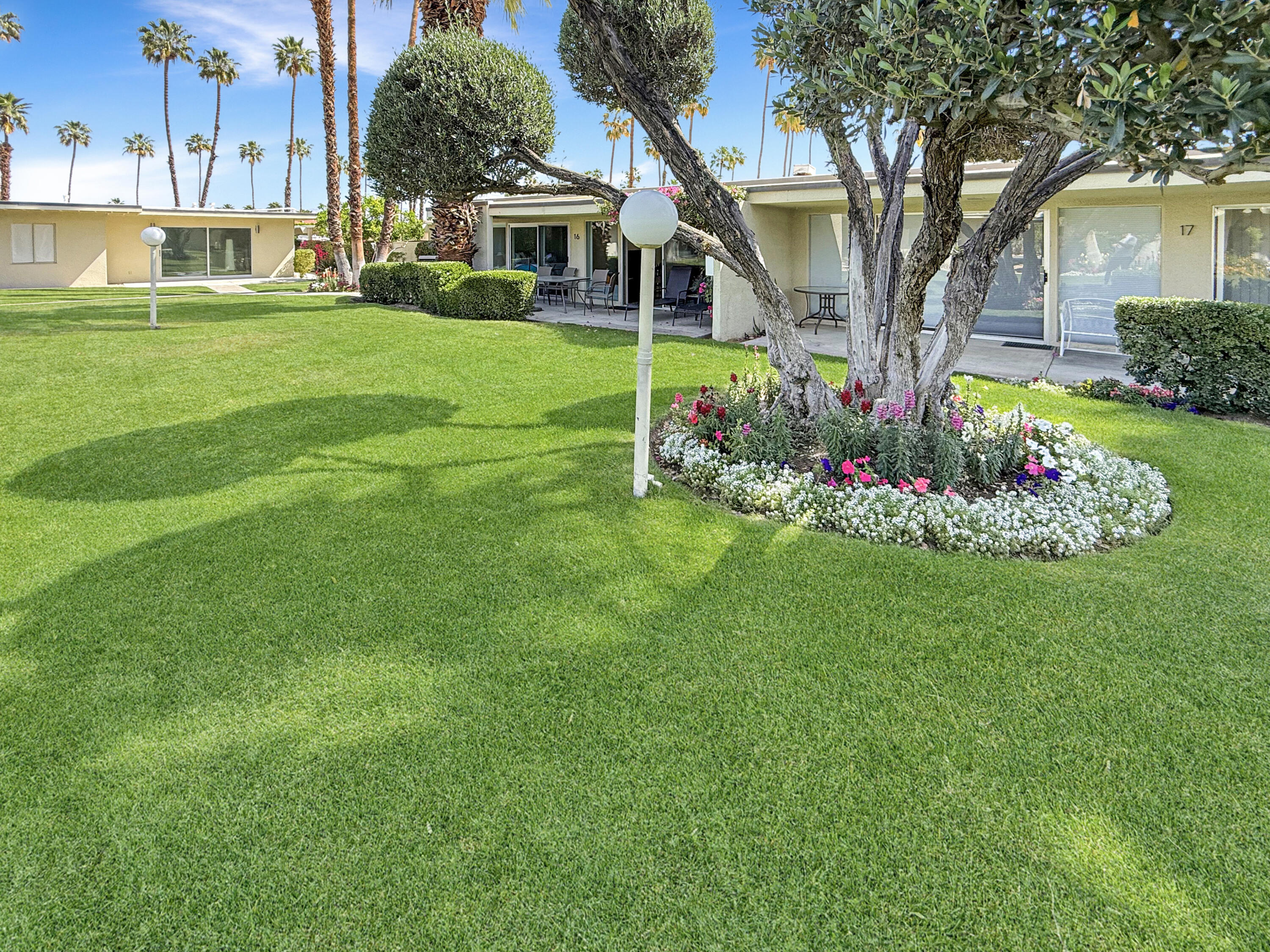 1881 South Araby Drive, Unit 16 Palm Springs, CA 92264 - Photo 32 of 52 a front view of a house with a yard table and chairs