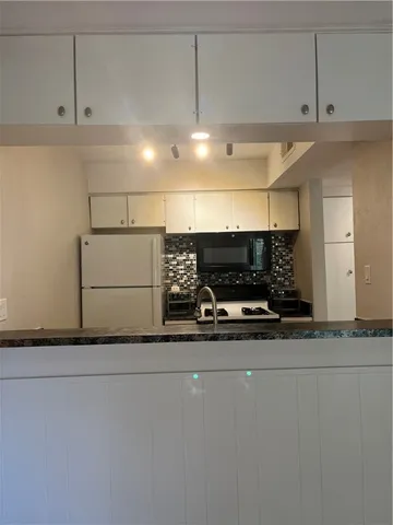 a view of kitchen with microwave and refrigerator