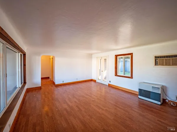 a view of an empty room with window and wooden floor