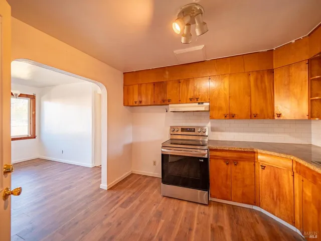 a kitchen with wooden floors and stainless steel appliances