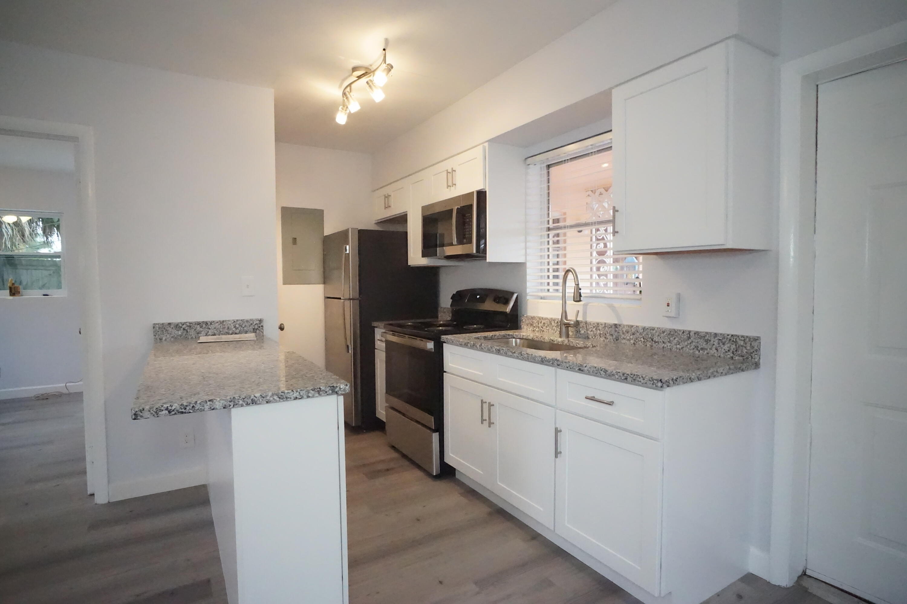 1815 Juno Road, Unit 3 North Palm Beach, FL 33408 - Photo 6 of 15 a kitchen with granite countertop cabinets stainless steel appliances a sink and a window
