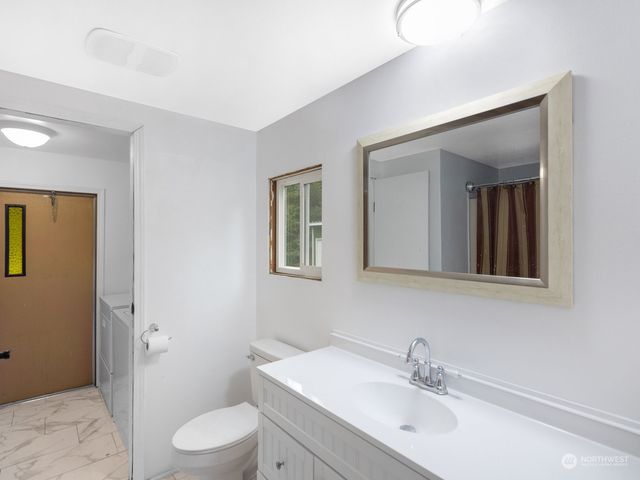 a bathroom with a toilet a sink a mirror and vanity