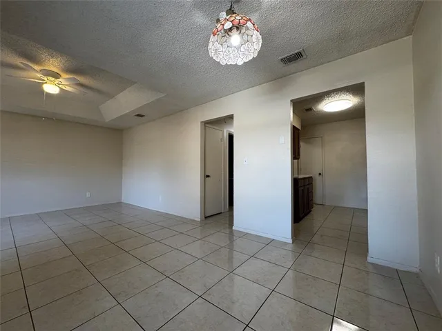 an empty room with kitchen and chandelier fan