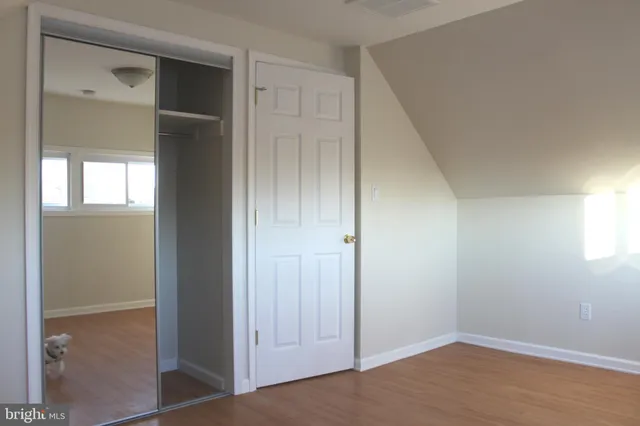 a view of an empty room with wooden floor and closet