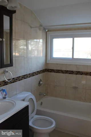 a bathroom with a granite countertop sink a toilet and bathtub