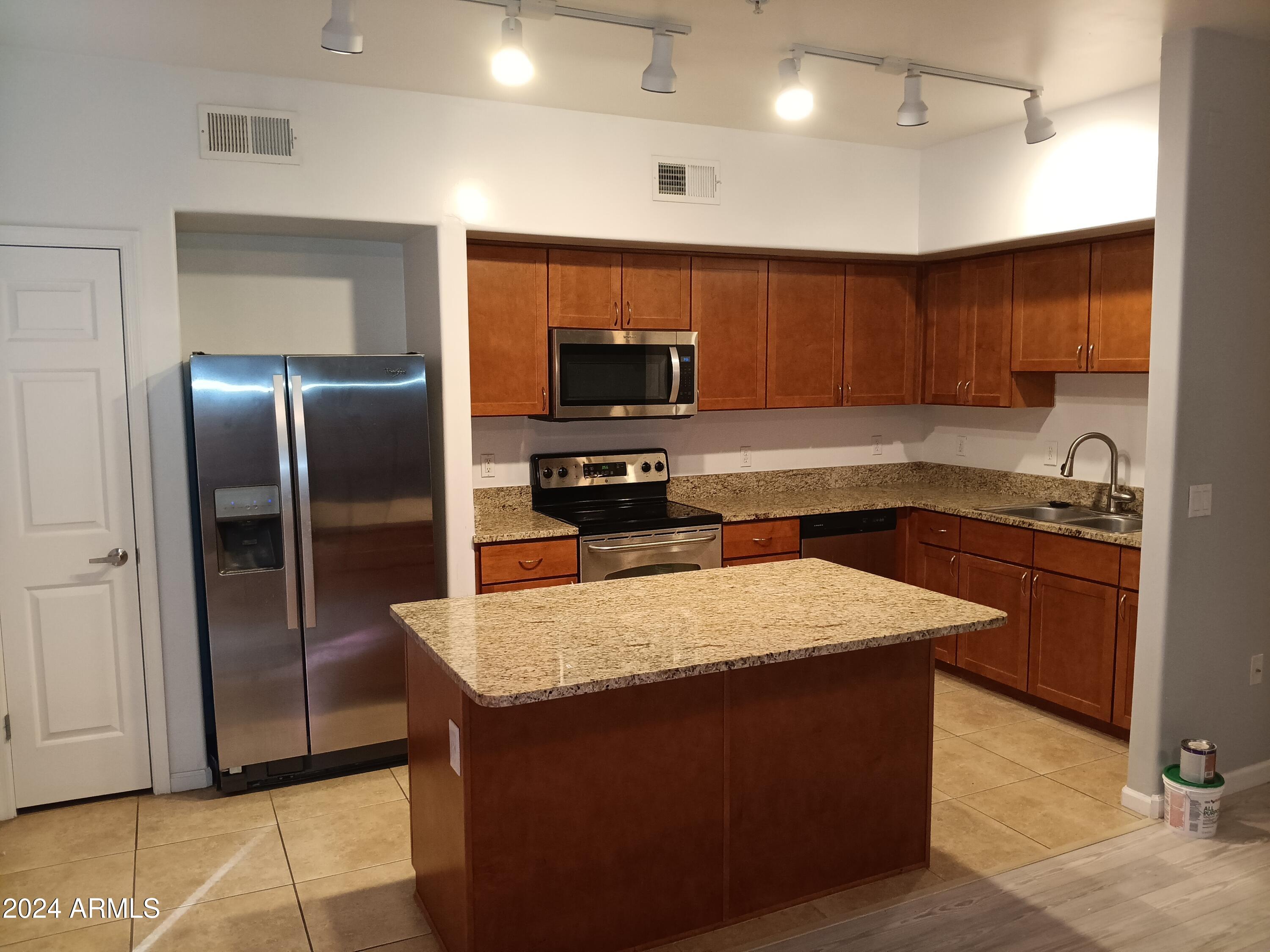 1920 East Bell Road, Unit 1103 Phoenix, AZ 85022 - Photo 11 of 29 a kitchen with granite countertop a refrigerator a sink and wooden cabinets