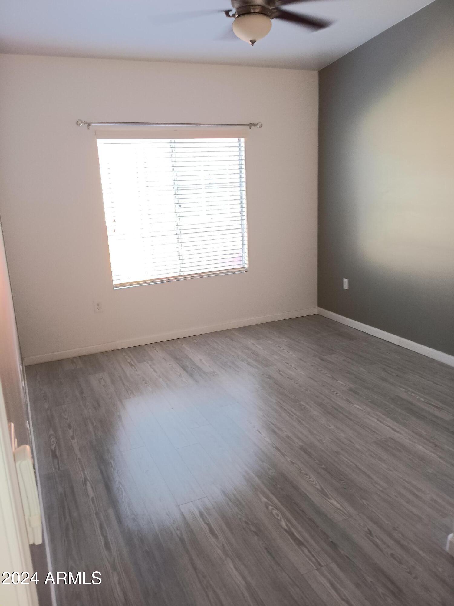1920 East Bell Road, Unit 1103 Phoenix, AZ 85022 - Photo 19 of 29 an empty room with wooden floor and windows