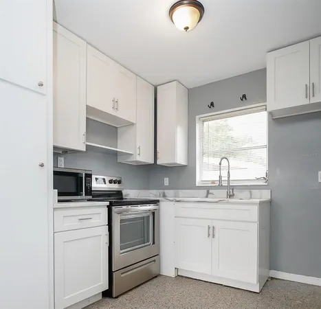 a kitchen with white cabinets white stainless steel appliances and sink
