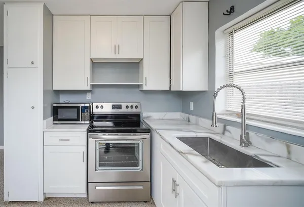 a kitchen with granite countertop a sink stove and cabinets